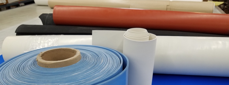 Inventory of rolls of materials for custom gaskets, pads and cushioning stacked in storage tubes.